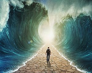 A man walking through the water with the waves parted.